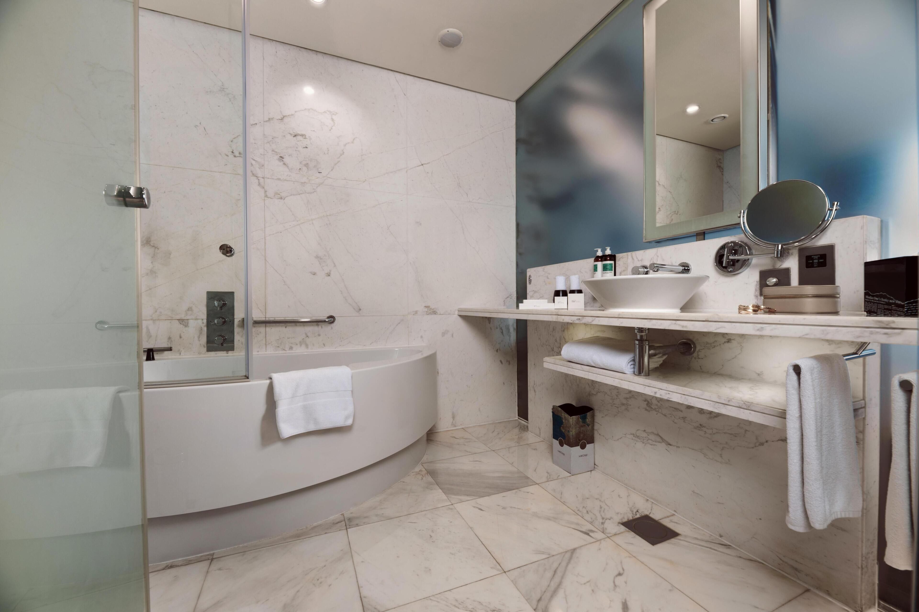 A modern bathroom with a glass-enclosed shower, a freestanding bathtub, and a vanity with a mirror and sink.