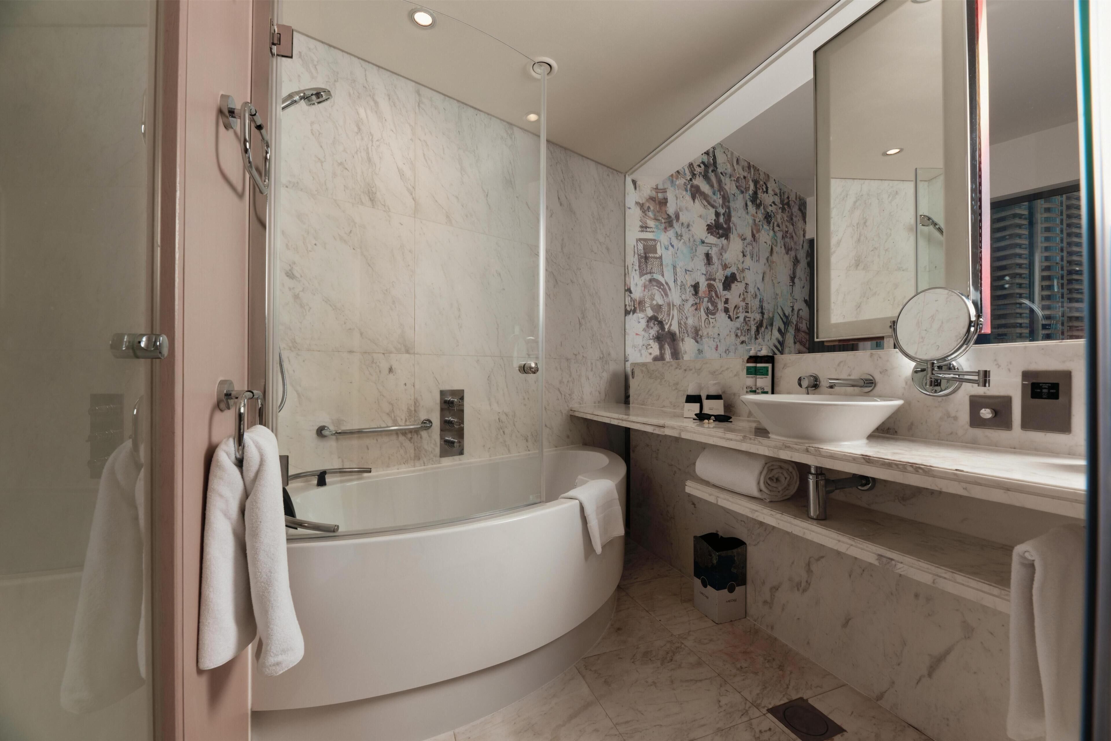 A modern bathroom with a freestanding bathtub, a large mirror, and a white sink.