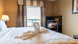 A hotel room with a bed, a TV, a fireplace, and a window with curtains. - Best Western Plus South Edmonton Inn & Suites (Edmonton)