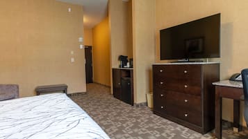 A hotel room with a bed, a dresser, a desk, a television, and a coffee maker.