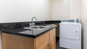 A small kitchen with a sink, wooden cabinets, and a white appliance.