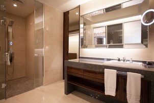 A modern bathroom with a glass-enclosed shower, a large mirror with a built-in light, and a granite countertop.