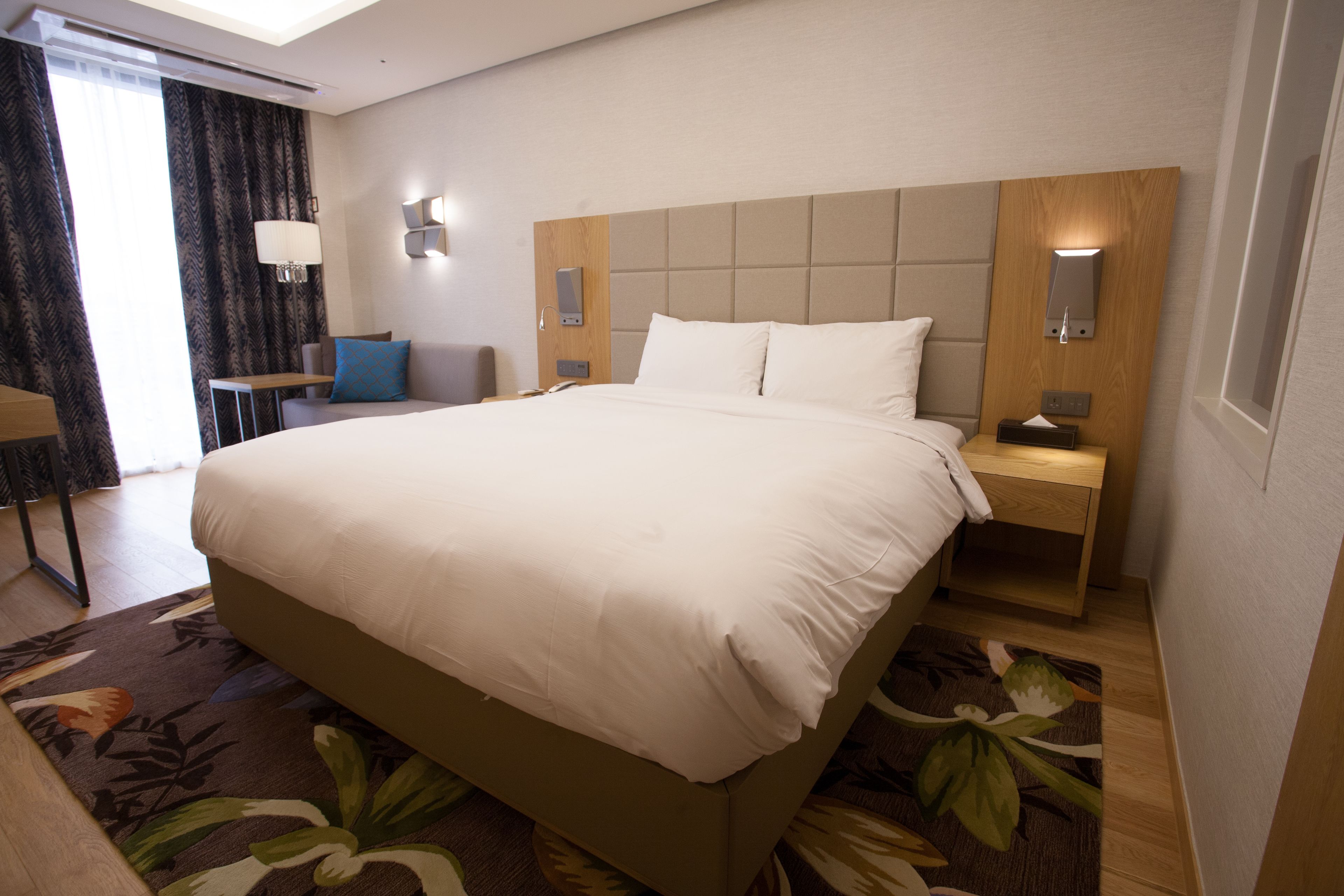 A hotel room with a large bed, bedside tables, a desk, and a chair.