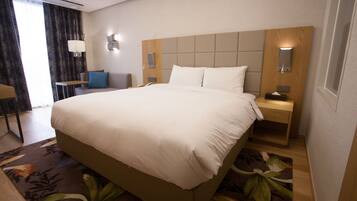 A hotel room with a large bed, bedside tables, a desk, and a chair.