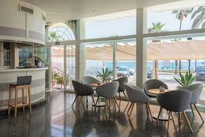 Un interior moderno con una zona de bar, asientos y ventanas amplias con vista al mar.