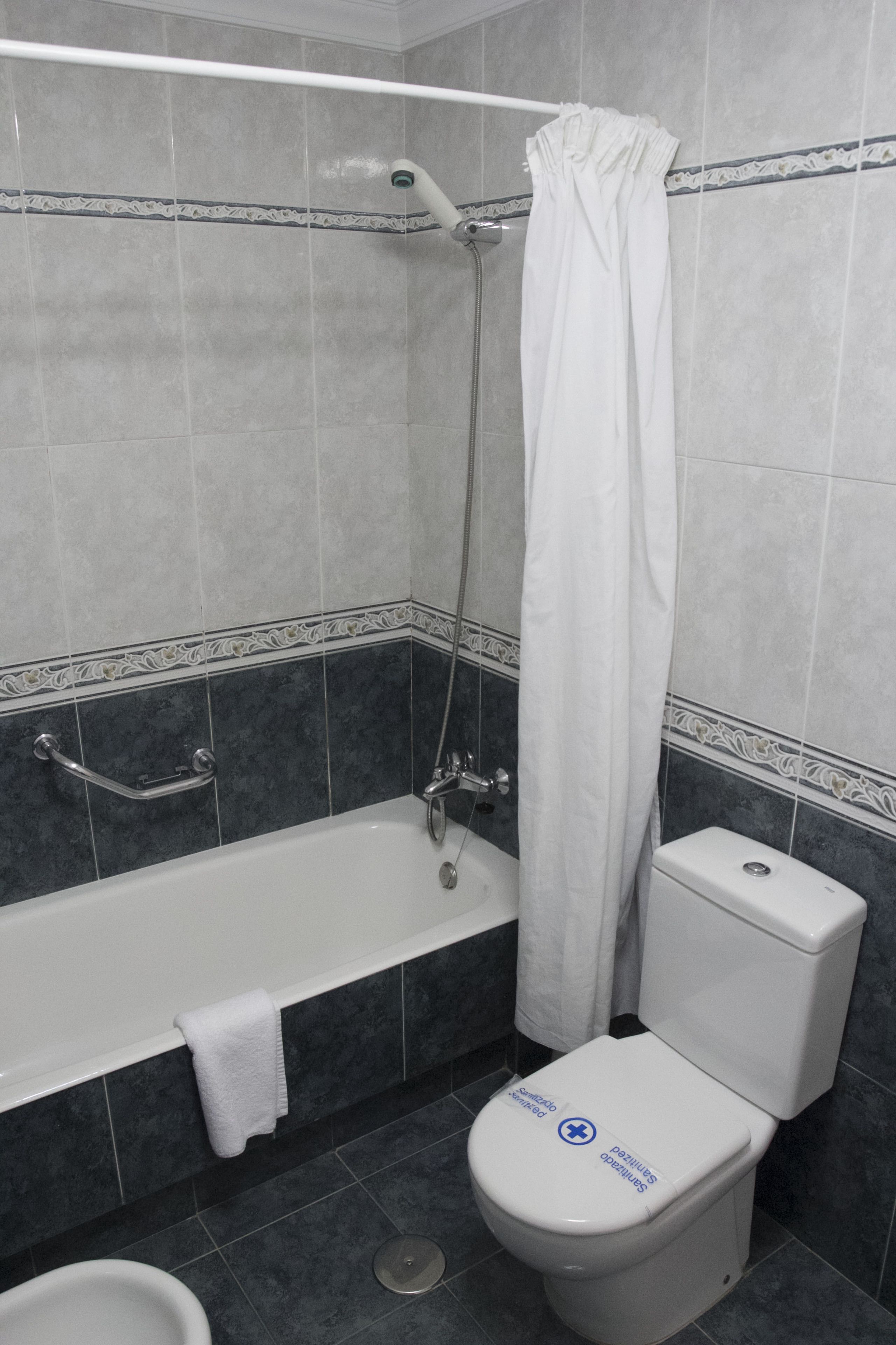 Een badkamer met een badkuip, toilet en douchegordijn.
