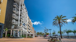 Un hotel de varios pisos con balcones, una entrada principal y vistas a la playa.