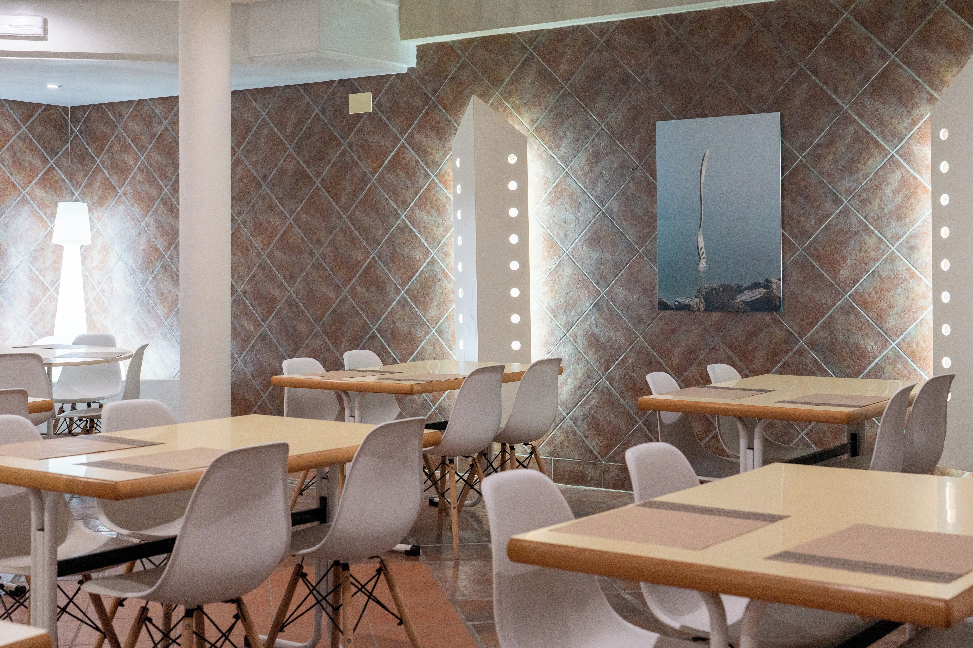 Interior de restaurante con paredes de azulejos, varias mesas y sillas.