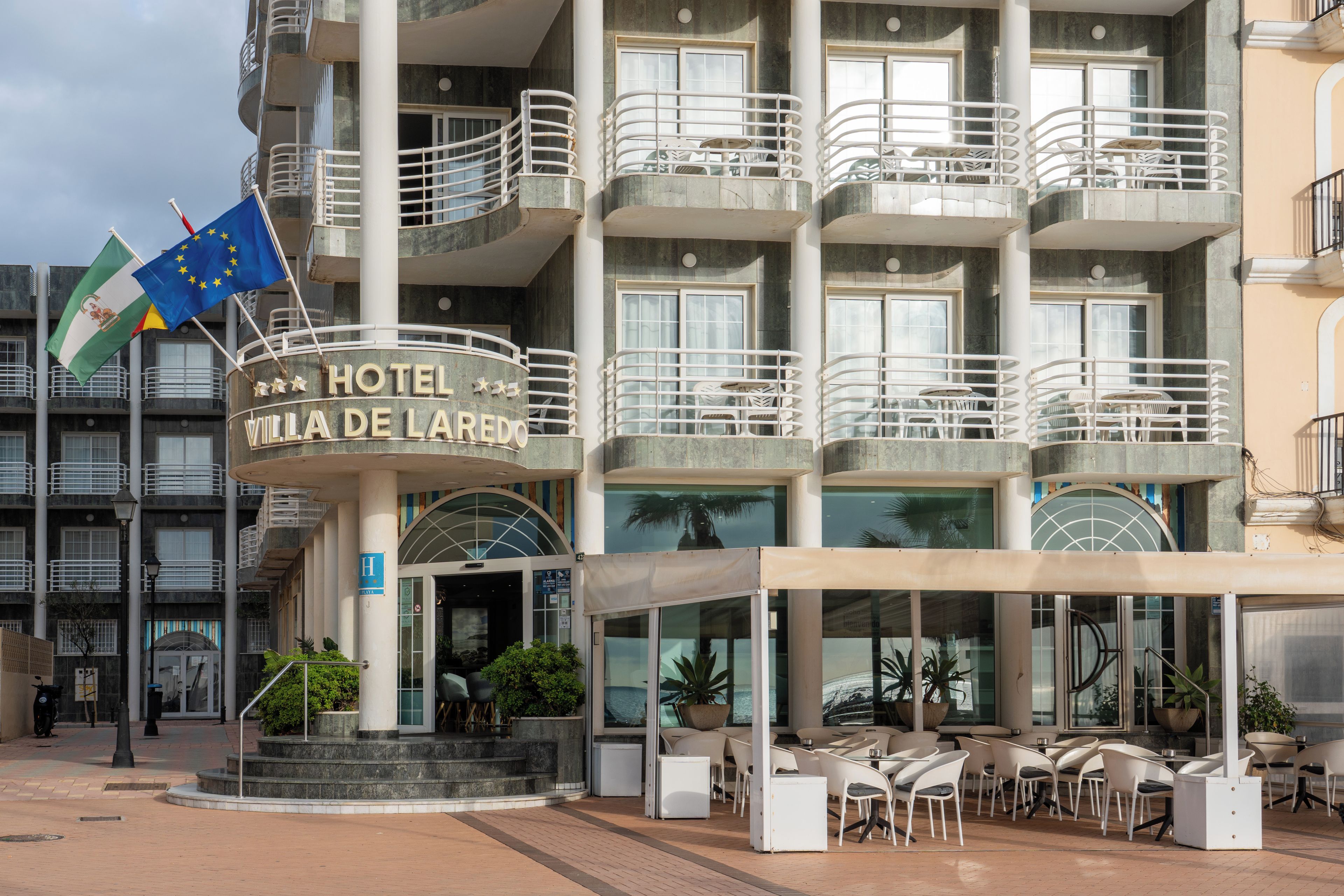 A hotel with a circular entrance, outdoor seating, and balconies.