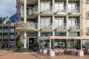 A hotel with a circular entrance, outdoor seating, and balconies.