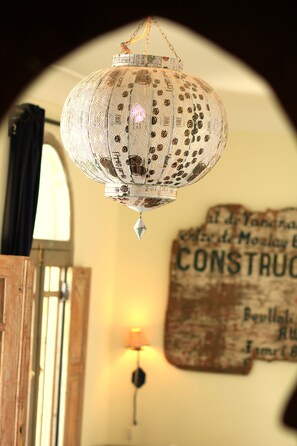 Un farol colgante con diseños intrincados, una puerta de madera y una pared con un letrero.