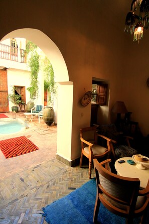 Un patio acogedor con piscina, muebles de madera y plantas en macetas.