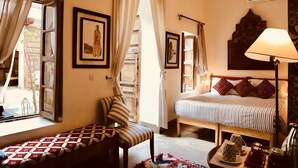 A cozy bedroom with a bed, a chair, a small table with cups, and a lamp. - Riad Le Coq Berbere (Marrakech)