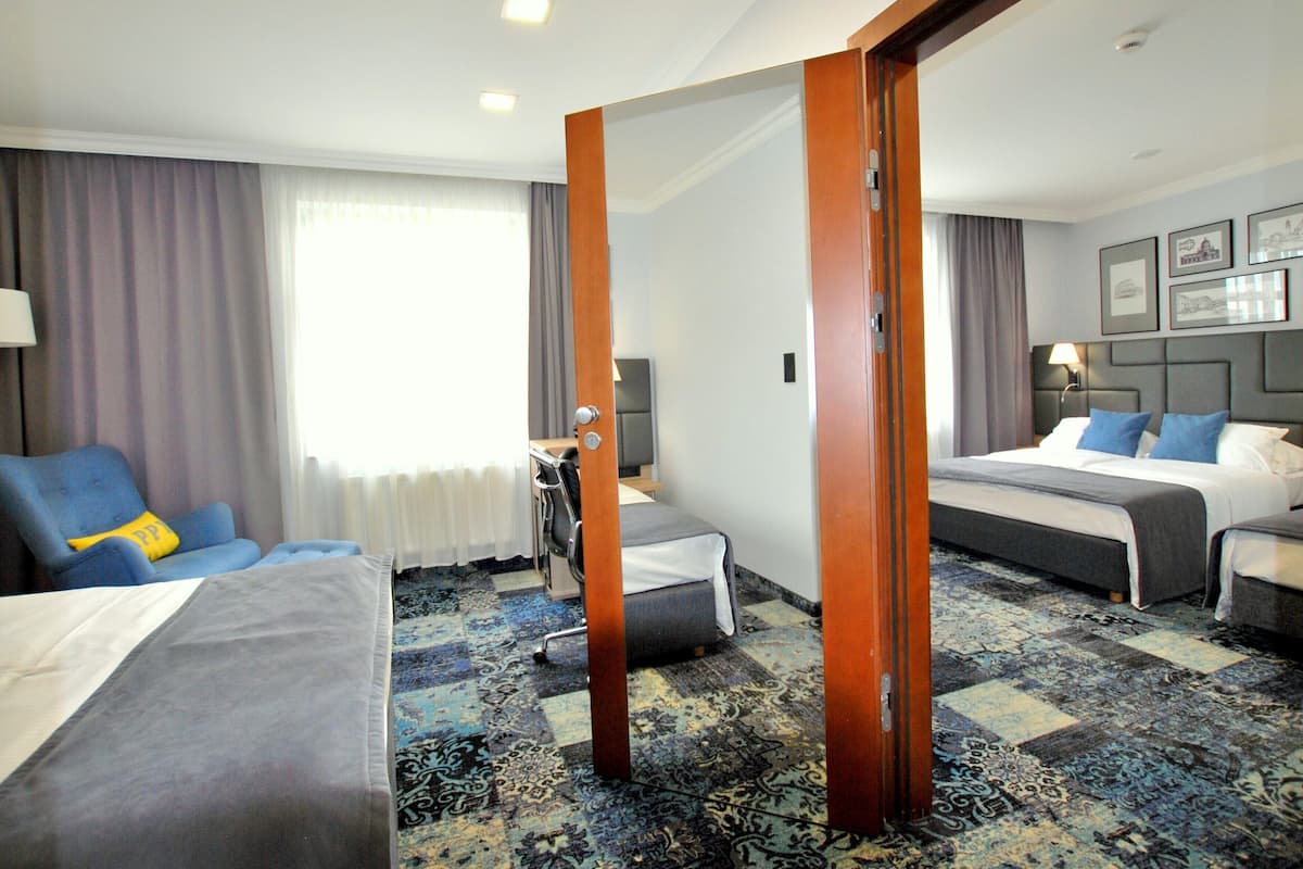A hotel room with a large bed, a smaller bed, a desk, a chair, and a large mirror.