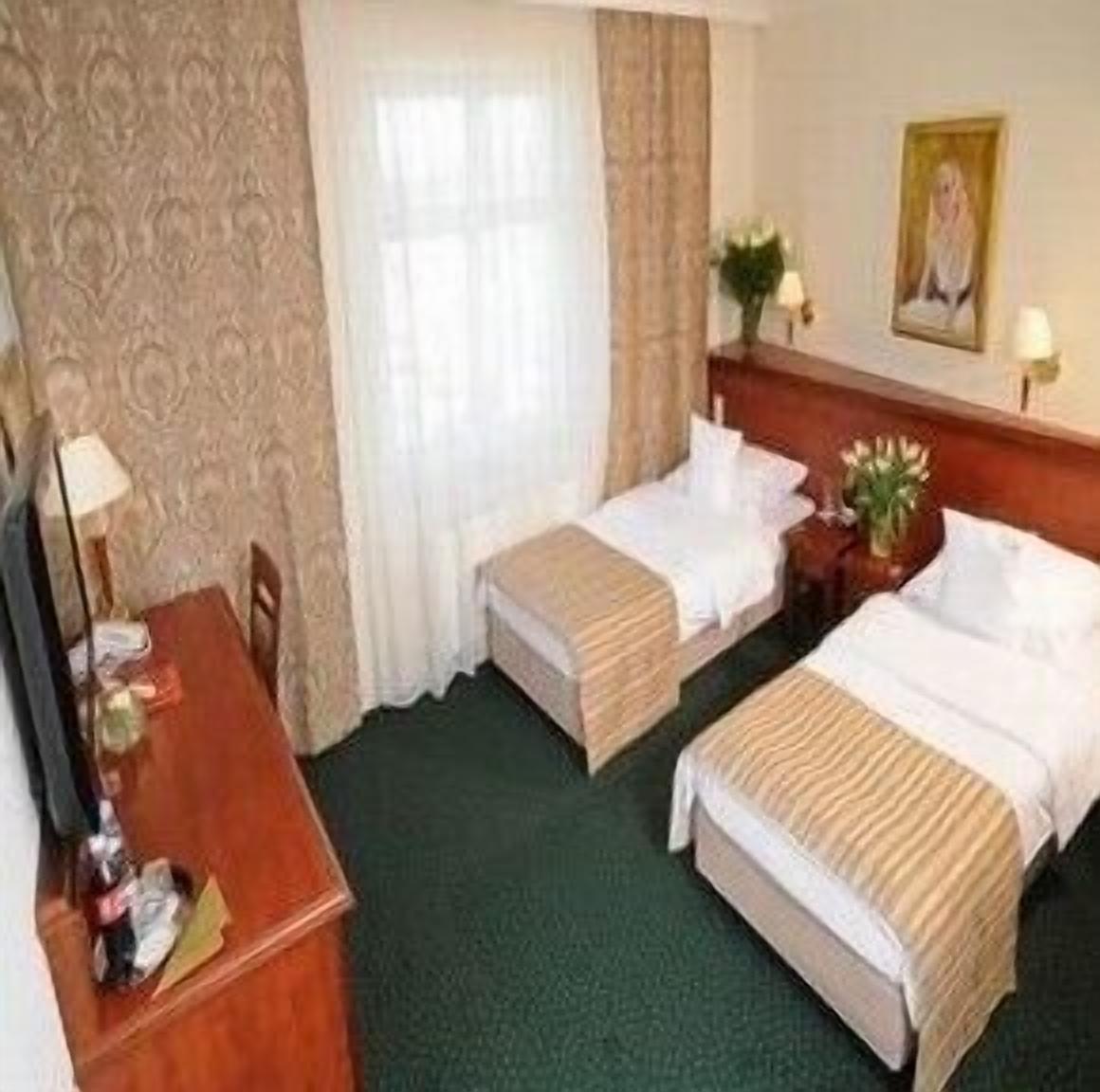 A hotel room with two beds, a desk, and a chair.