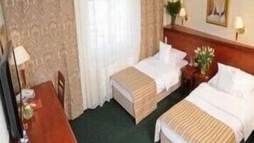 A hotel room with two beds, a desk, and a chair.