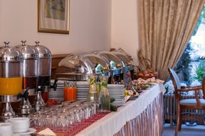 A buffet setup with various food items and beverages, including a fruit display and a beverage station with multiple drink dispensers. - Hotel Wloski (Poznan)