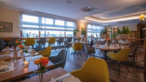Un restaurante con varias mesas, sillas y velas.