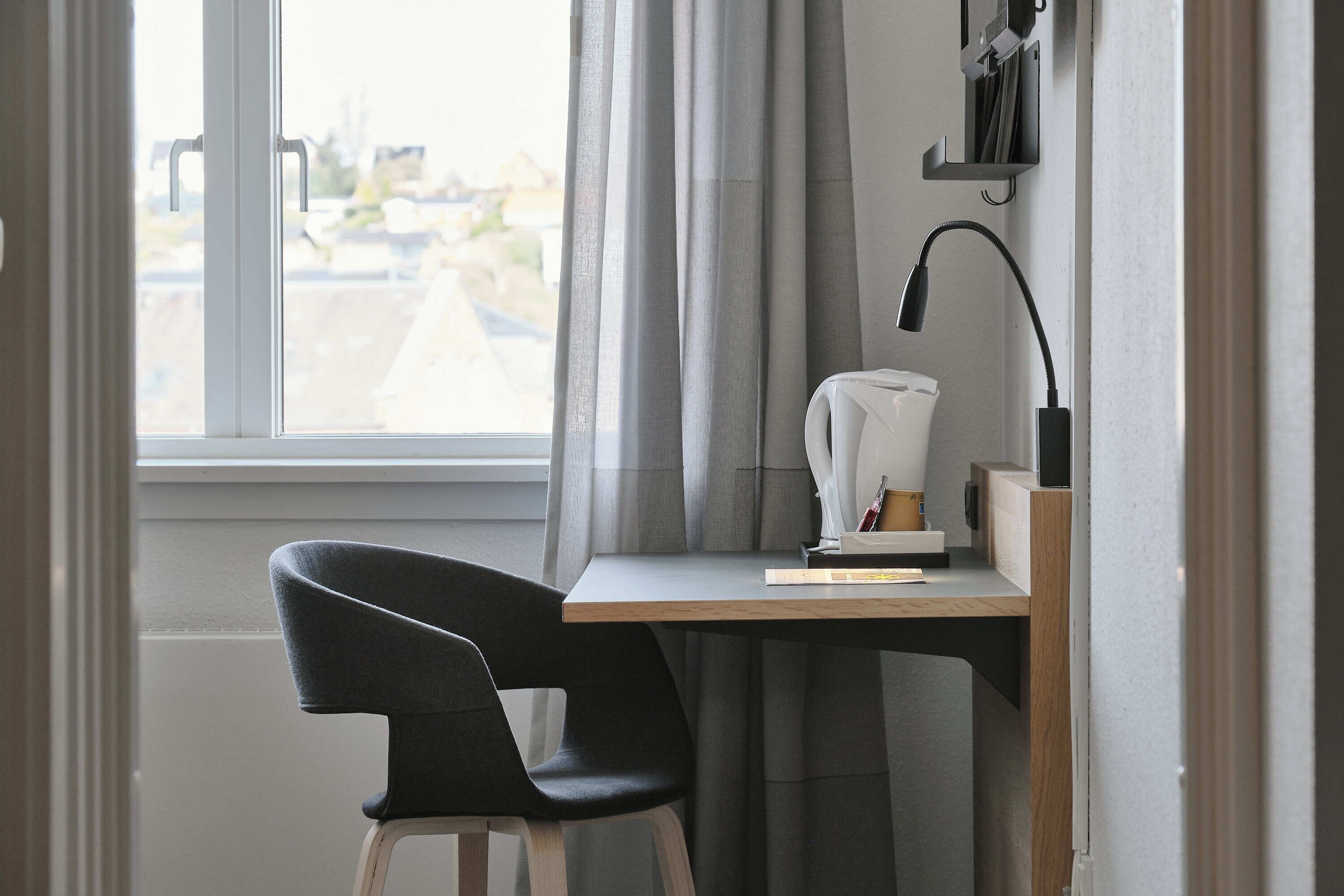A modern workspace with a desk, chair, and a window with curtains.