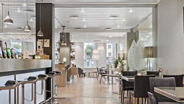 A modern restaurant interior with bar stools, tables, and hanging pendant lights. - Hotel Svendborg (Svendborg)
