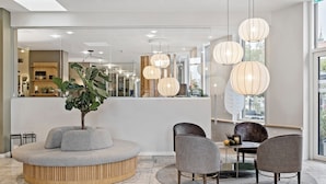 A modern hotel lobby with a round seating area, a reception desk, and hanging pendant lights. - Hotel Svendborg (Svendborg)