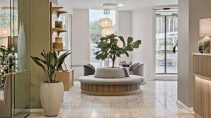 A modern lobby with a round seating area, large potted plants, and a glass wall. - Hotel Svendborg (Svendborg)