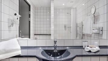 Un baño moderno con un lavabo negro, azulejos blancos, un perchero y un espejo.