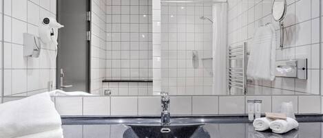 A modern bathroom with a black sink, white tiles, a towel rack, and a mirror.