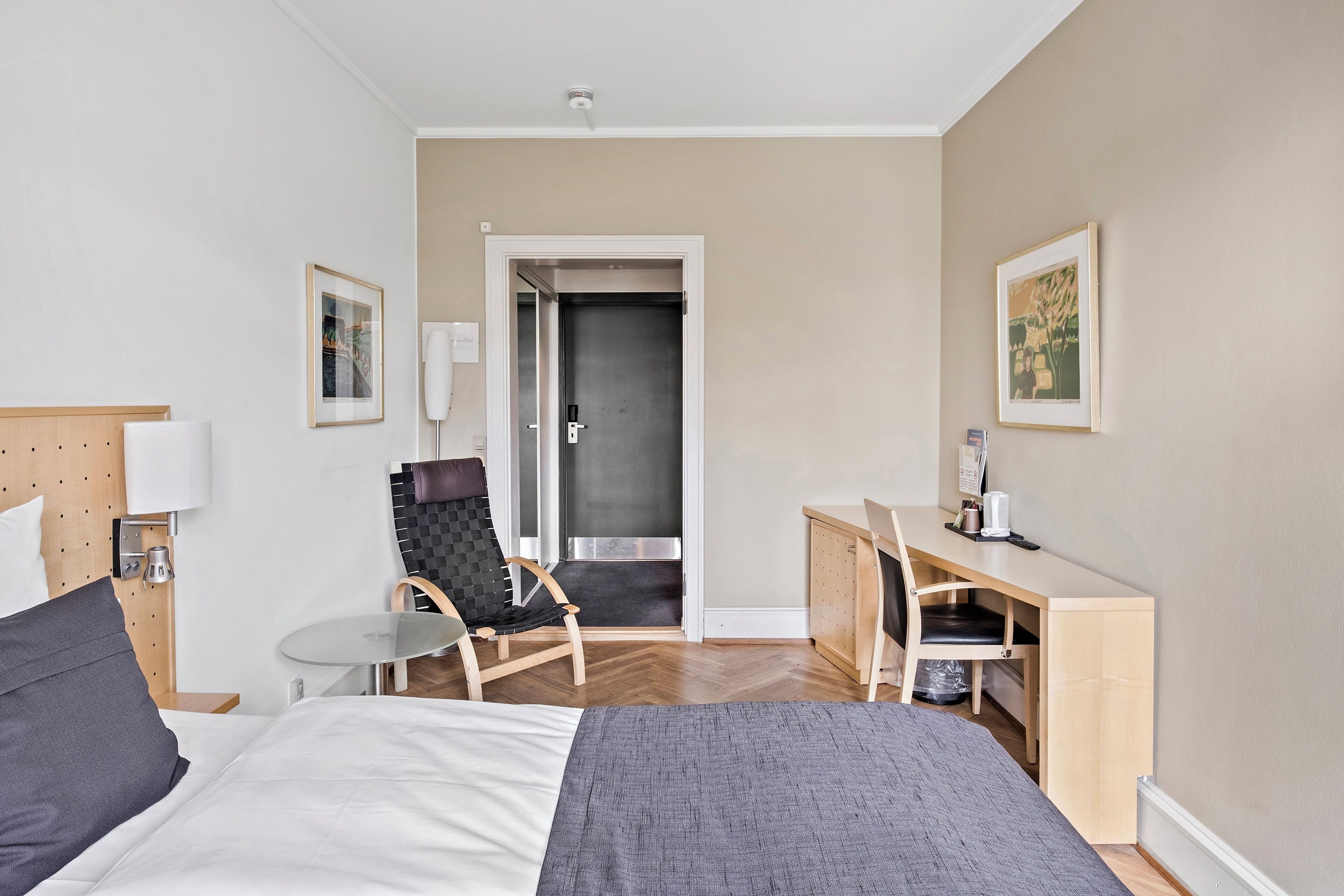 Una habitación de hotel con cama, escritorio, silla y una mesita.
