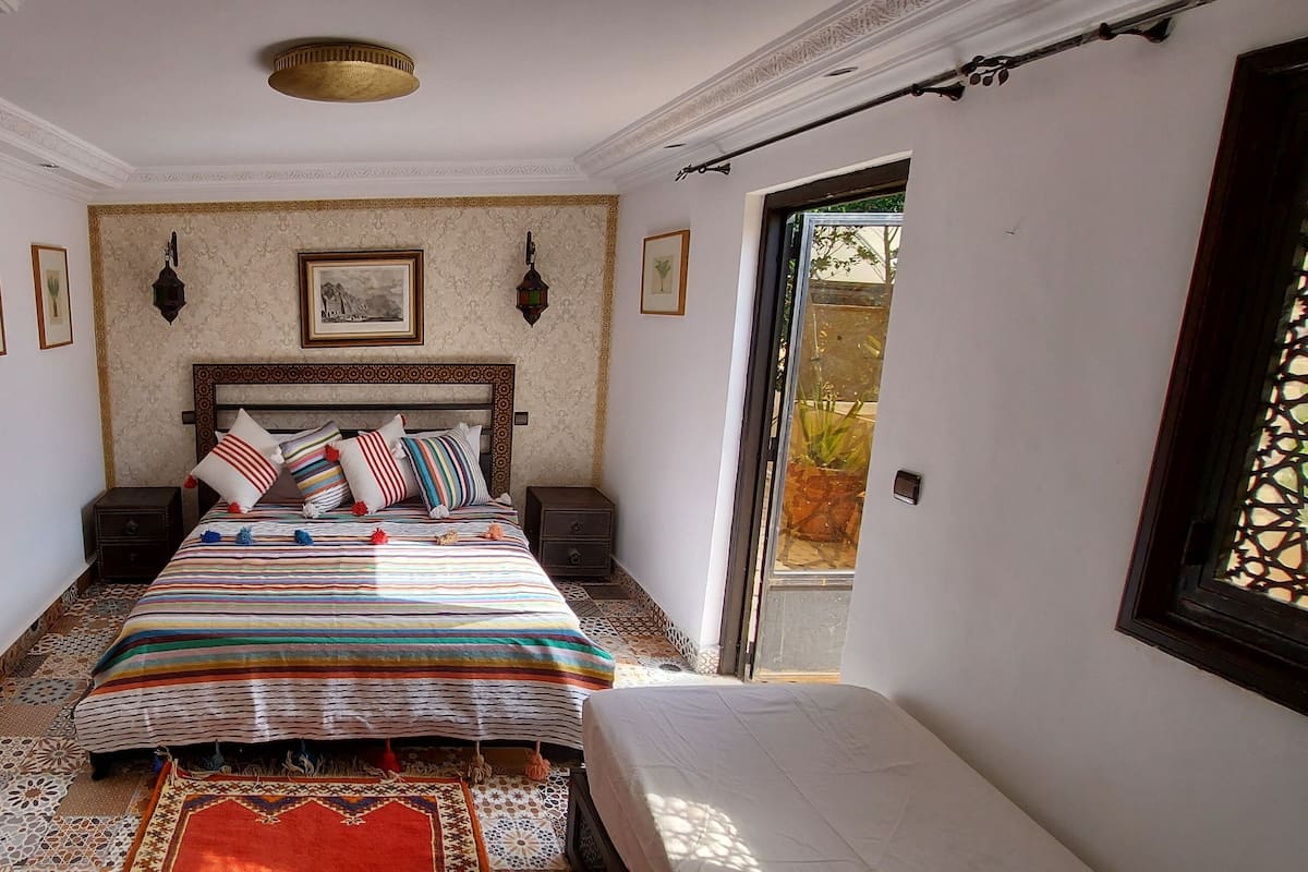 Una camera da letto con un letto, comodini, un tappeto decorato e una finestra con vista.