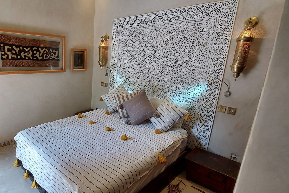 Una camera da letto con un letto, opere d'arte incorniciate, un pannello decorativo e luci a parete.