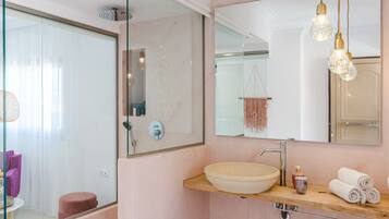 A modern bathroom with a large mirror, a sink, and a shower.