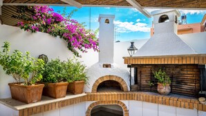 An outdoor patio with a brick oven, potted plants, and a white wall. - Malia Mare (Hersonissos)