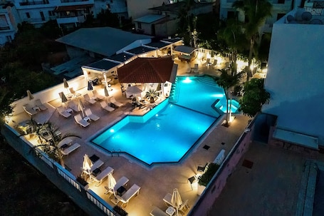 Una piscina al aire libre, sombrillas, sillones reclinables de piscina