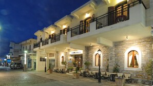A hotel with outdoor seating, stone walls, and multiple balconies. - Malia Mare (Hersonissos)