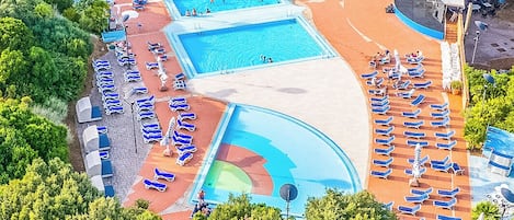 A resort with multiple swimming pools, sun loungers, and a tennis court.