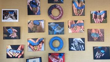 A wall with multiple framed photographs of hands holding medals and ribbons, a blue wreath, and a framed letter.