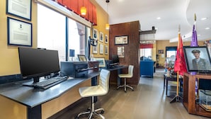 Een receptiegedeelte met een balie, computer, stoelen, ingelijste certificaten en vlaggen.