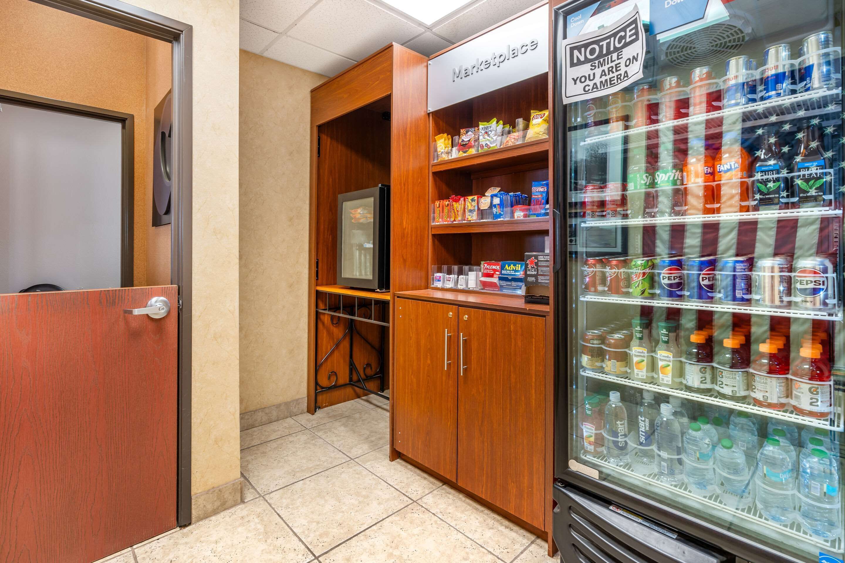 A kitchenette with a refrigerator, microwave, and wooden cabinets.