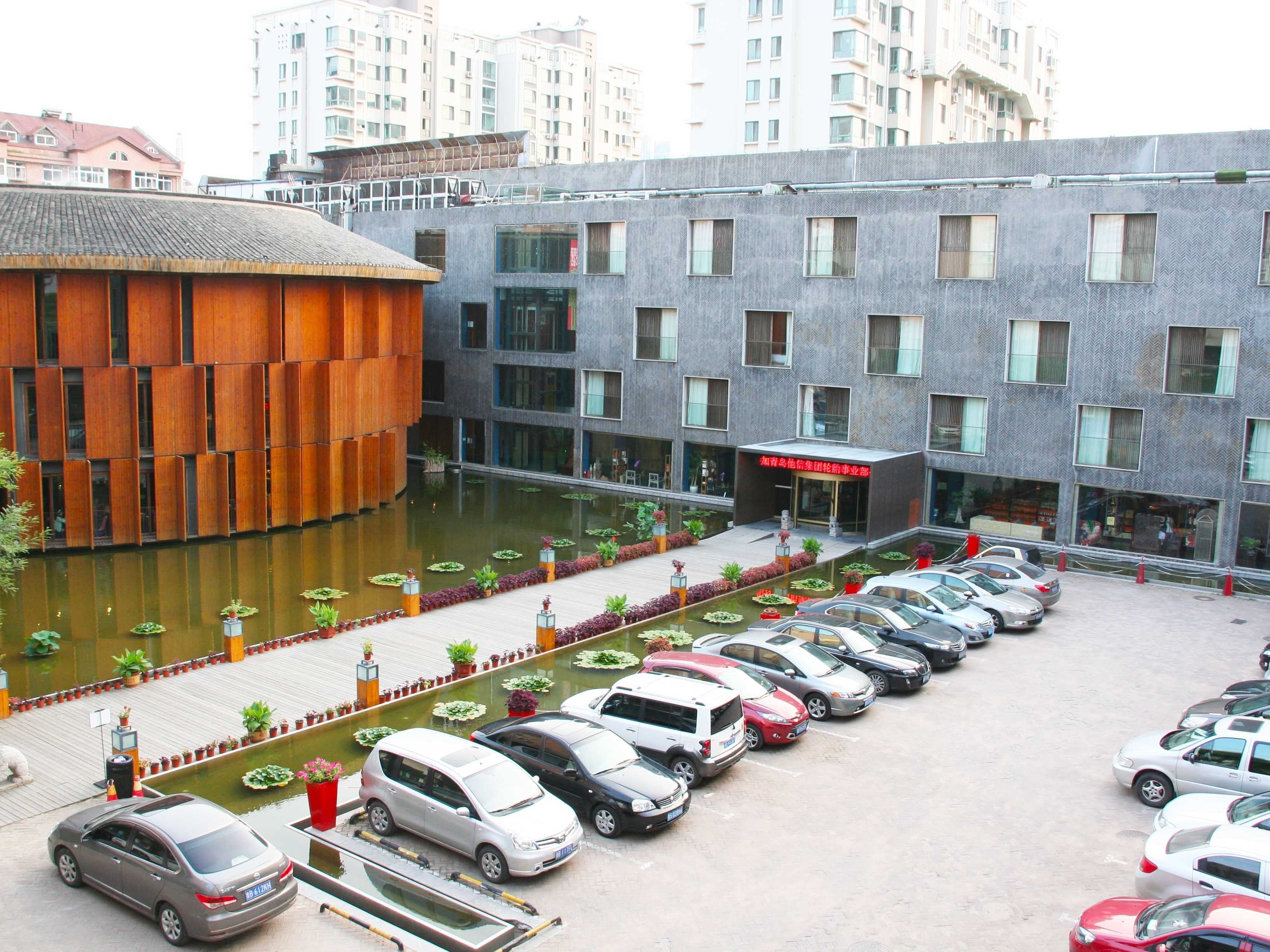 Een modern gebouw met een parkeerplaats en een waterpartij.