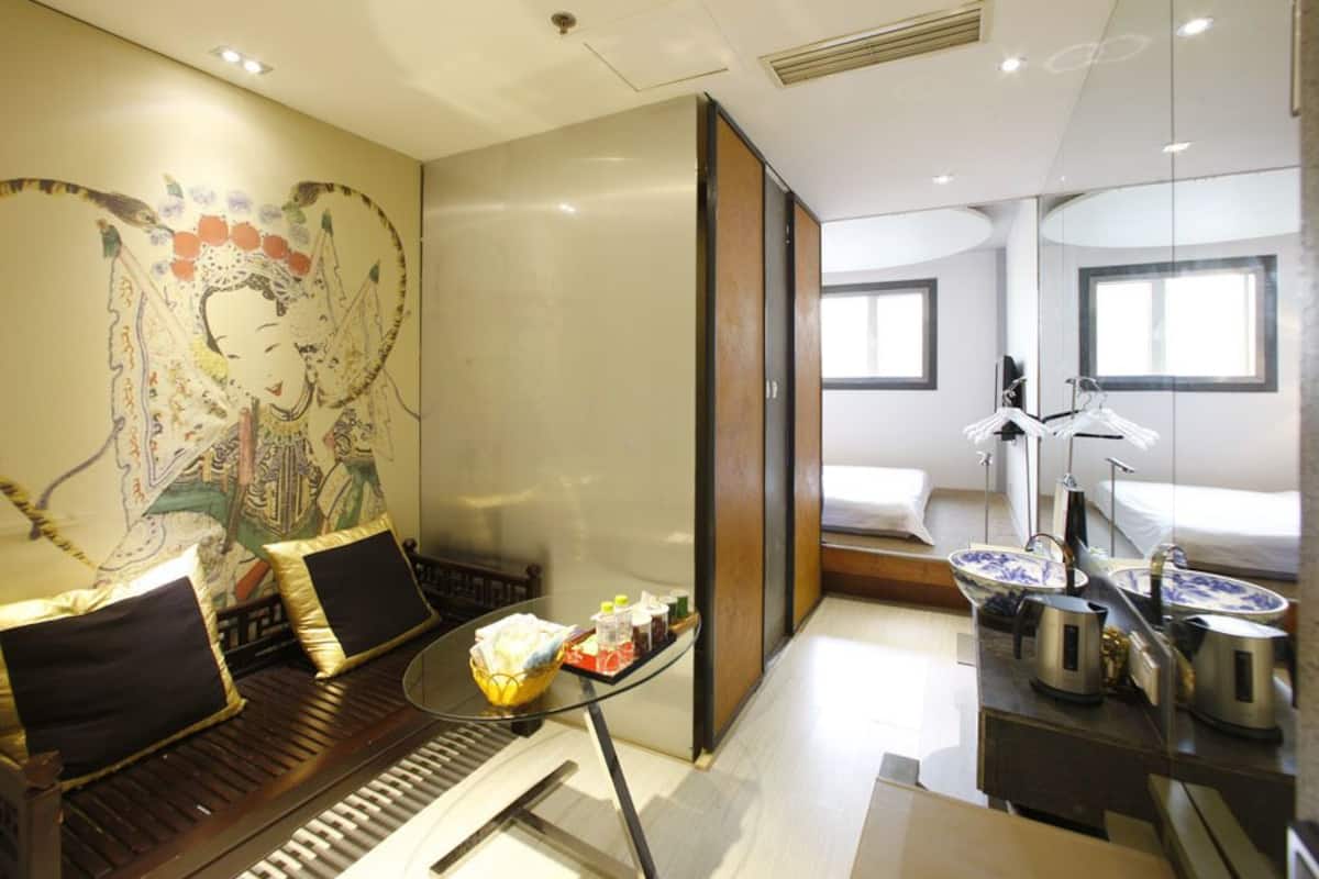 A modern hotel room with a traditional mural, a dining area with a table and chairs, and a kitchenette.