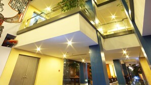 A multi-level hotel interior with glass railings, indoor plants, and a traditional door. - China Community Art Habitat Hotel (Qingdao)