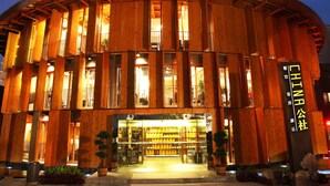A wooden building with a circular facade and a sign indicating it is a hotel. - China Community Art Habitat Hotel (Qingdao)