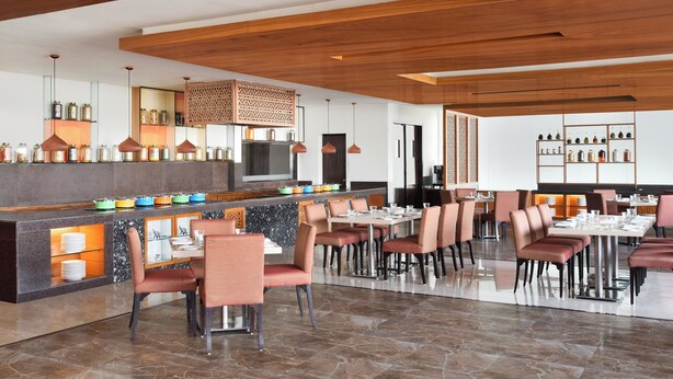 Un restaurant moderne avec un plafond en bois, un bar central agrémenté de bols colorés et différents types de sièges.