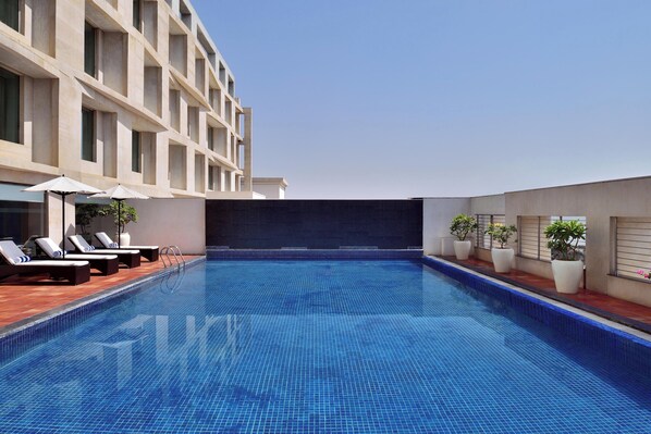 A rooftop swimming pool with lounge chairs and potted plants. - Four Points by Sheraton Jaipur, City Square (Jaipur)