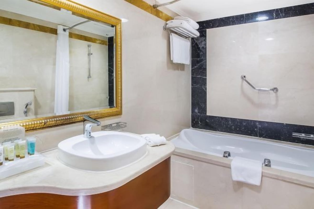 A bathroom with a sink, mirror, and bathtub.