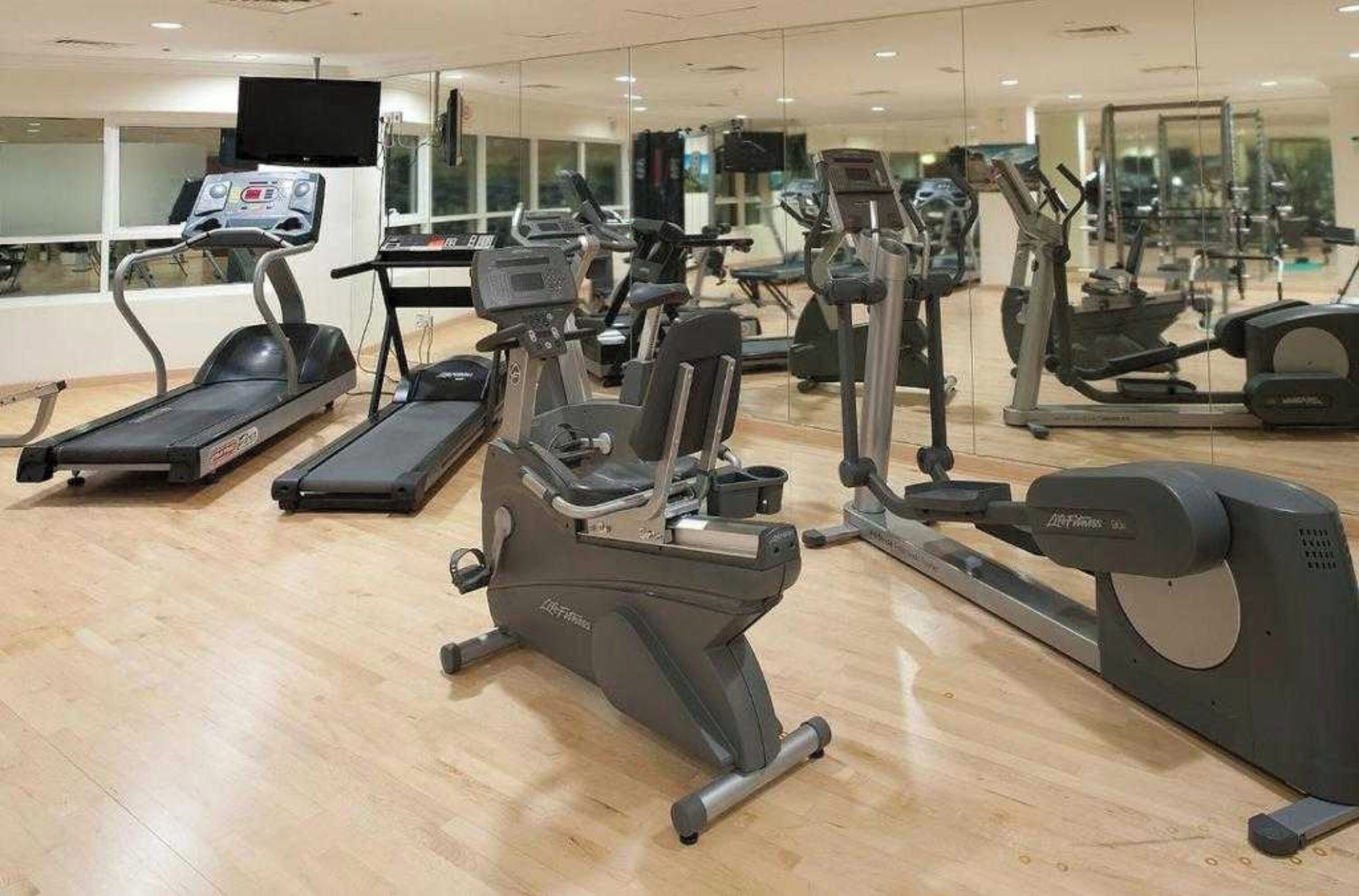 Un gimnasio con cintas de correr, elípticas y bicicletas estáticas.