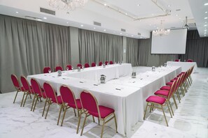 A conference room with a long table, red chairs, and a projector screen. - Ker Recoleta Hotel (Buenos Aires)