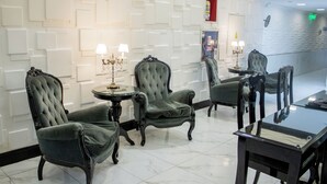 A room with a modern design, featuring tufted armchairs, a glass-top table, and a decorative wall with recessed lighting. - Ker Recoleta Hotel (Buenos Aires)