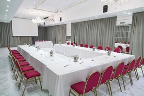 A conference room with a long table, chairs, a projector screen, and a chandelier. - Ker Recoleta Hotel (Buenos Aires)